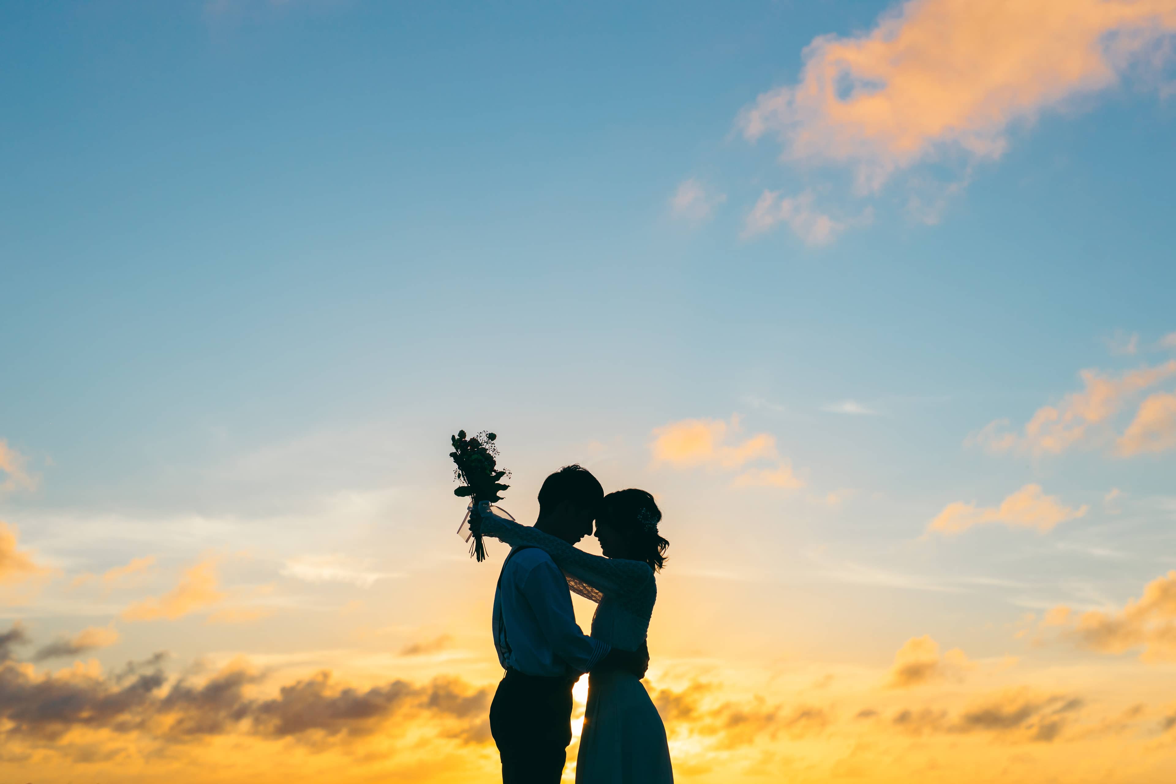 宮古島でのウェディングフォト撮影：夕焼けを背景にキスをするウェディング姿のカップルのシルエット